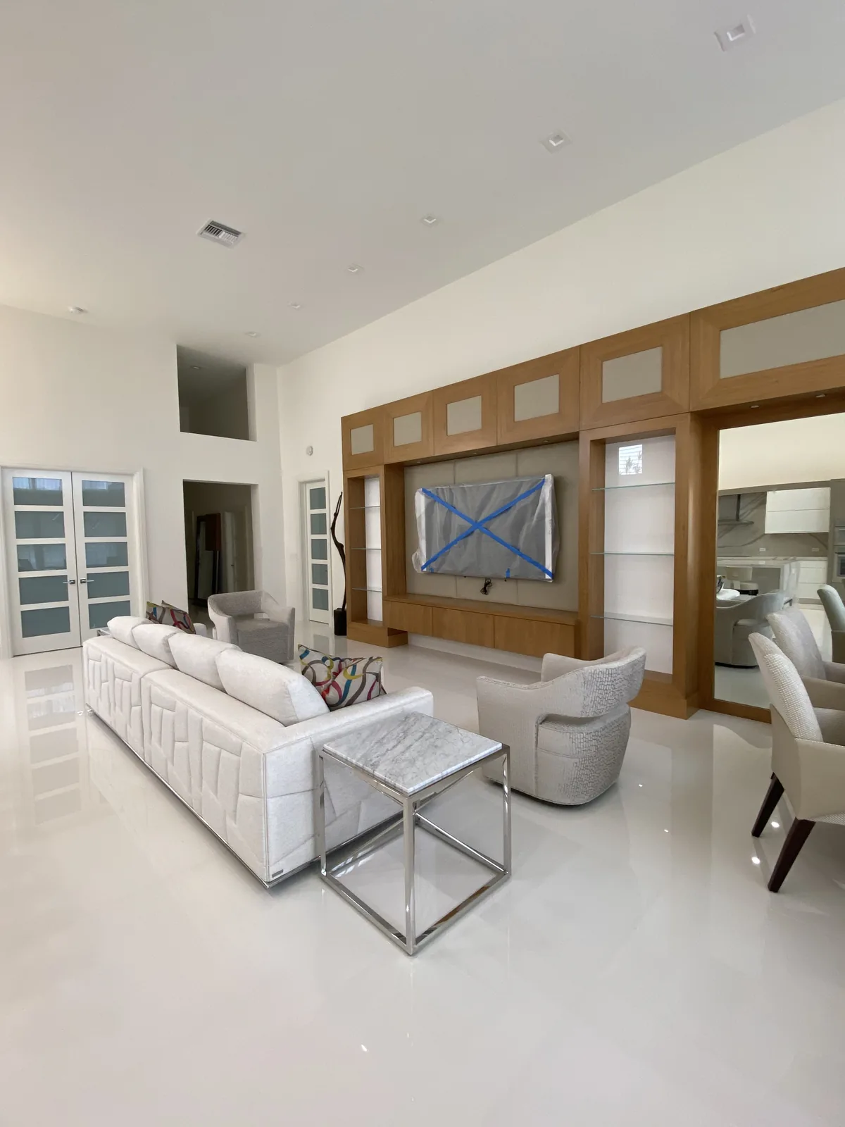 White sectional, wood media wall, and marble coffee table.