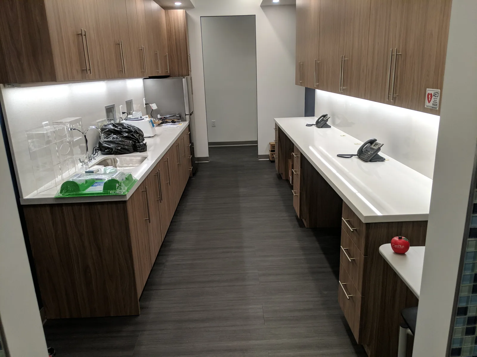 Break room with wood cabinetry, white countertops, and stainless appliances.