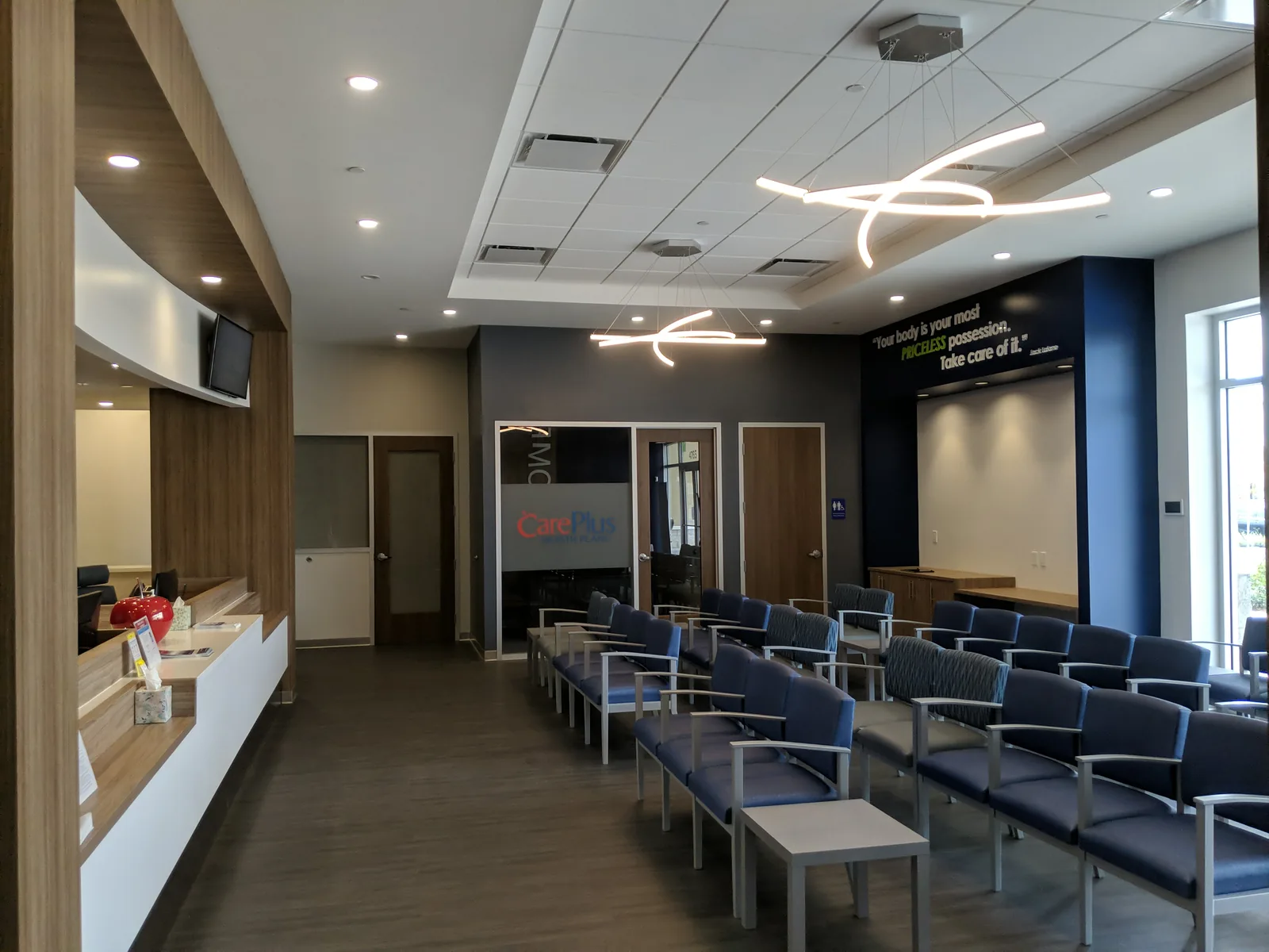 Medical clinic waiting area with reception desk and neon signage detail.