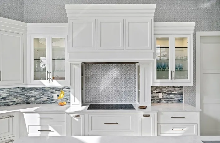 White kitchen with custom cabinetry, granite countertops, decorative tile backsplash.