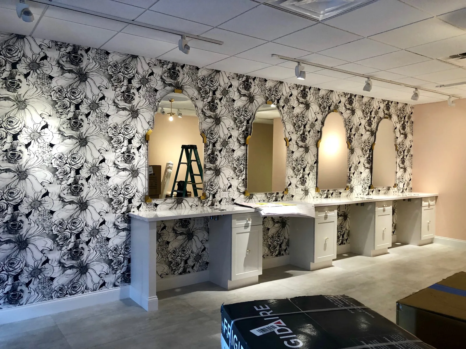 Bathroom vanity with floral wallpaper, multiple mirrors, and marble countertops.