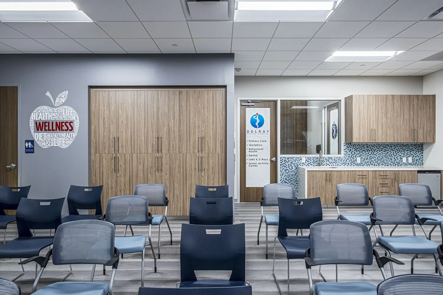 Medical clinic waiting room with blue mesh chairs and wellness signage.