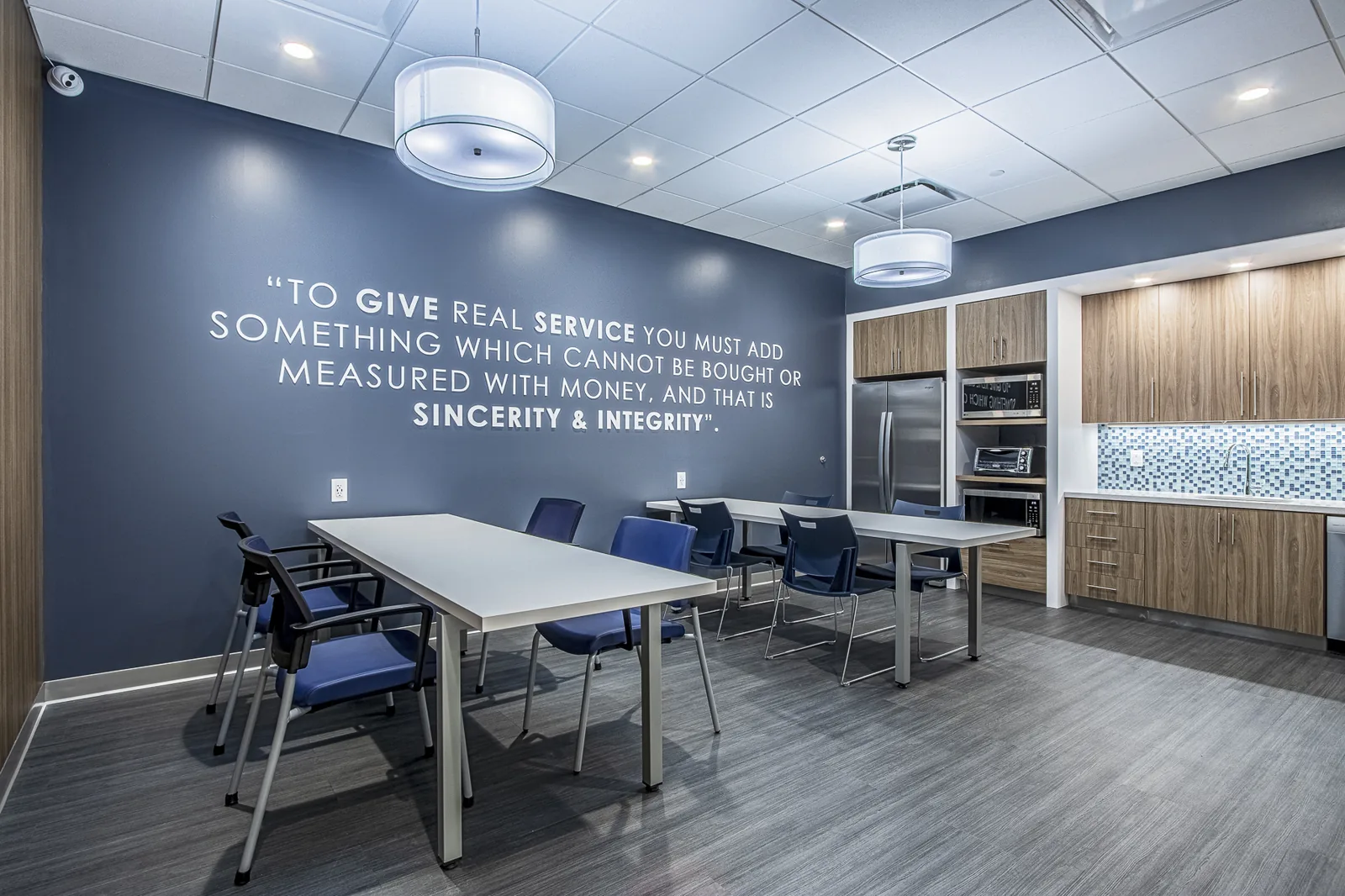 Commercial office breakroom with inspirational wall quote and blue seating.