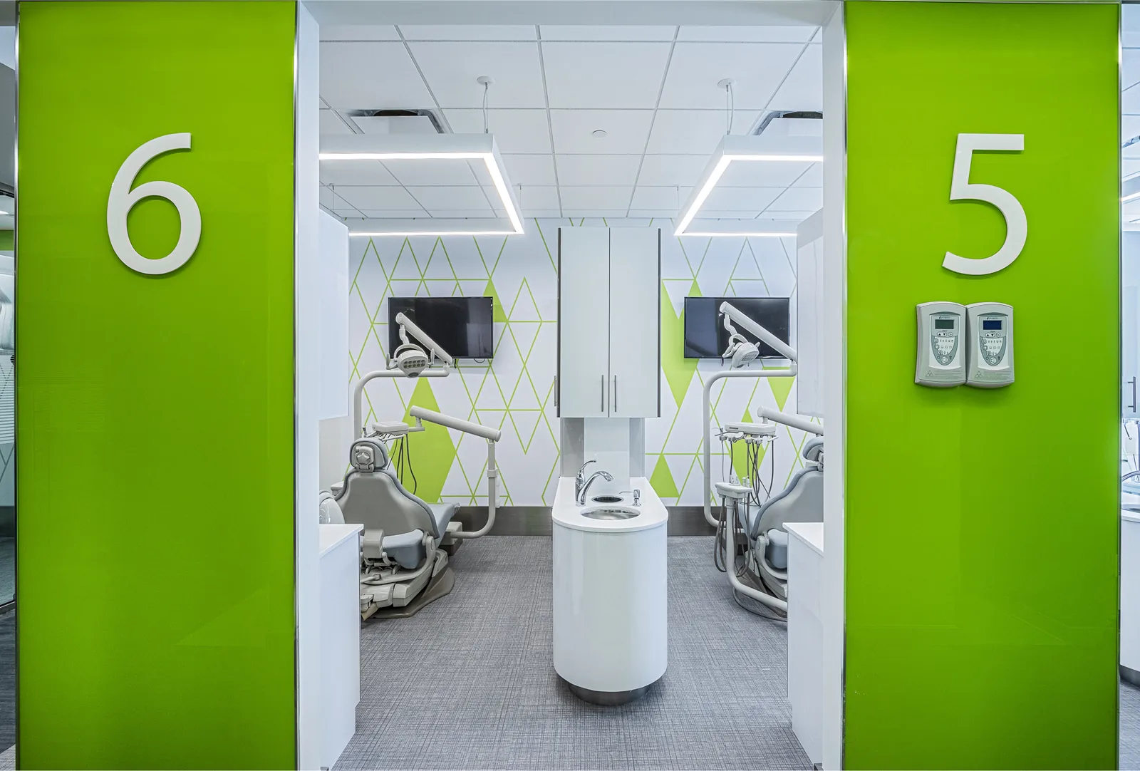 Bright dental operatory with green accent walls and numbered treatment rooms.