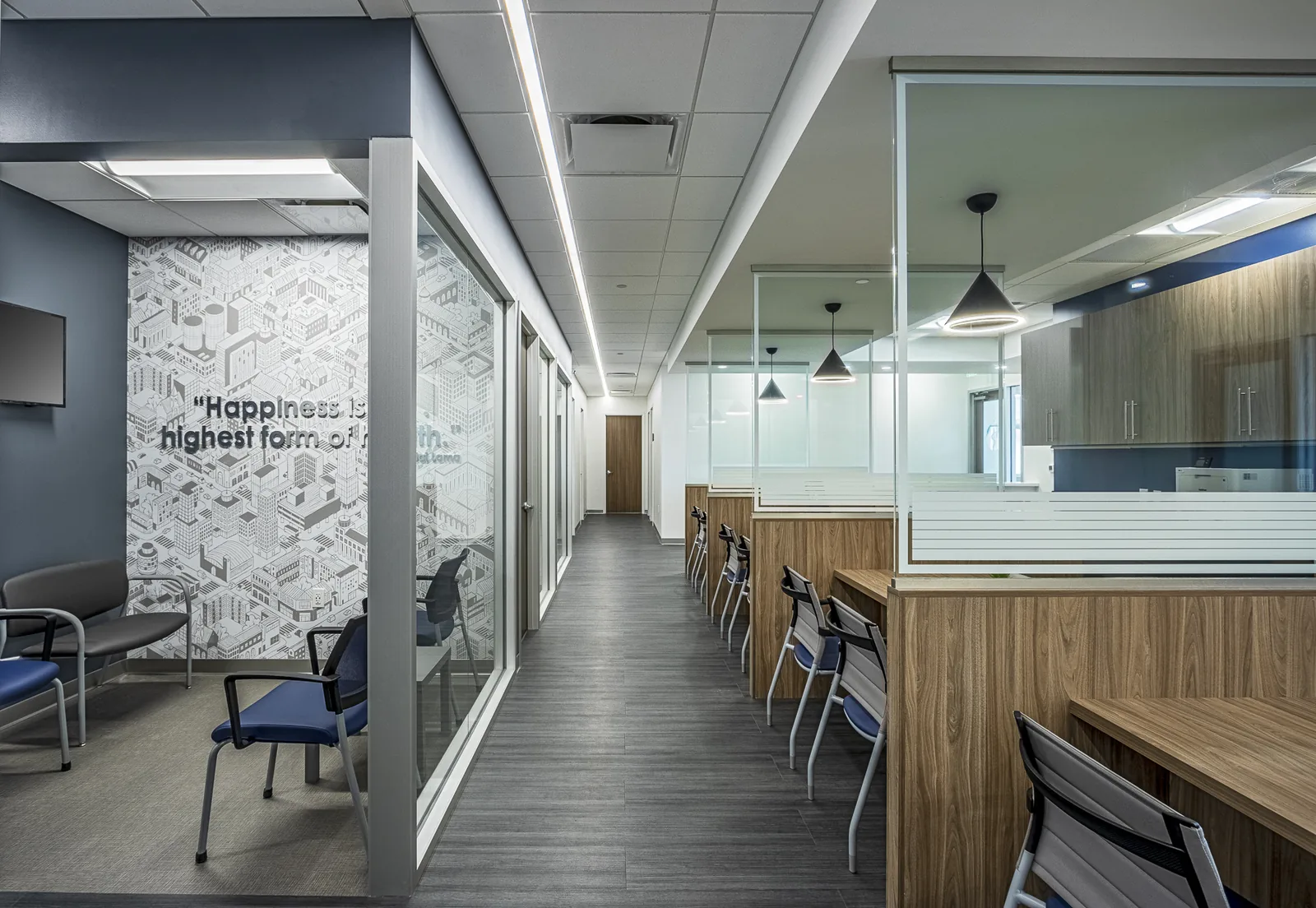 Office corridor with glass-walled meeting rooms and collaborative workspace.