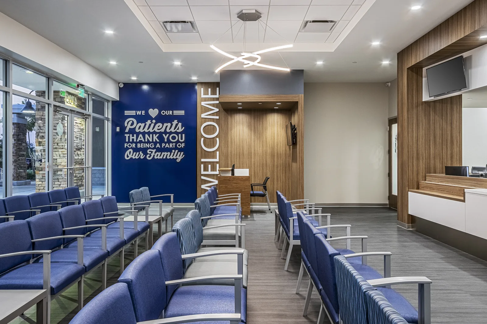Medical clinic waiting room with blue seating and patient-appreciation signage.