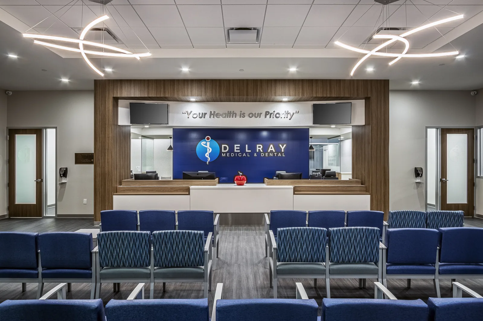 Medical clinic reception with blue seating and dental branding on back wall.